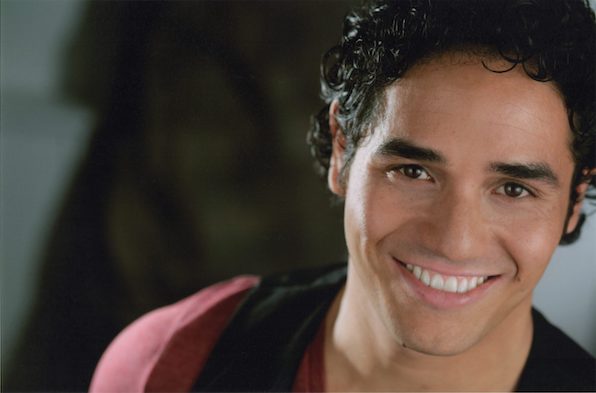 Adam Jacobs smiling. Black vest, maroon t-shirt. 