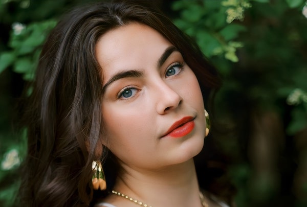 Stella Katherine Cole in white dress, earrings and lipstick head tilted.